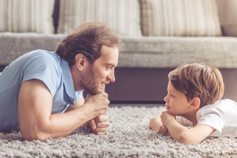 Side view of handsome father and his cute son looking at each other and smiling